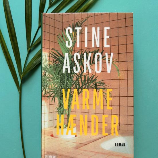 Foto af Stine Askovs bog "Varme hænder", der ligger ovenpå et blad