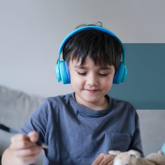 En dreng lytter med høretelefoner på mens han tegner.