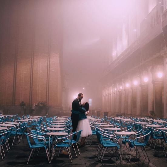 Par, der holder om hinanden midt imellem en masse caféborde og stole