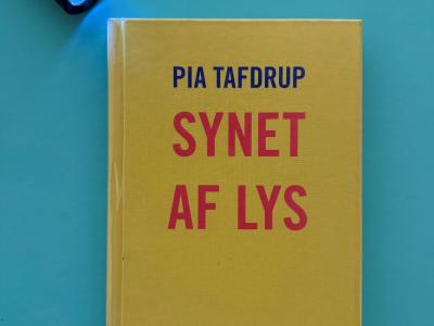 Foto af lommelygter der lyser på bogen "Synet af lys" af Pia Tafdrup